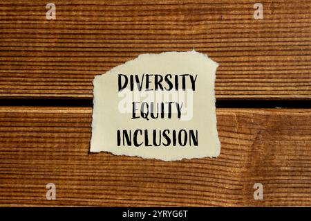 Diversity Equity e Inclusion Message scritto su carta strappata con sfondo in legno. Diversità concettuale equità e inclusione del simbolo DEI. Copia Foto Stock