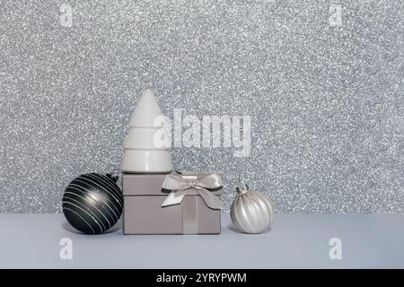 Confezione regalo in argento con nastro in raso e ornamenti su sfondo scintillante e scintillante che evocano un'atmosfera di lusso per le vacanze. Copia spazio. Foto Stock