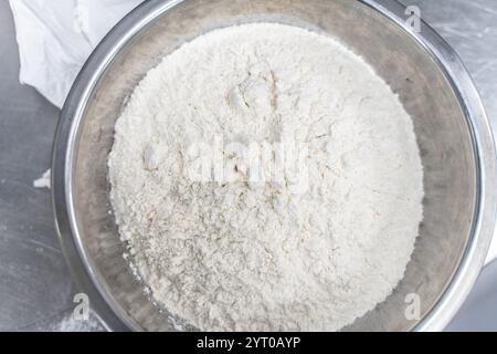 Farina di grano in una ciotola di acciaio sul tavolo di produzione in una panetteria. Primo piano. Vista dall'alto. Foto di alta qualità Foto Stock