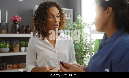 Donne che discutono i dettagli del prodotto in un negozio di arredamento con piante e scaffali sullo sfondo Foto Stock