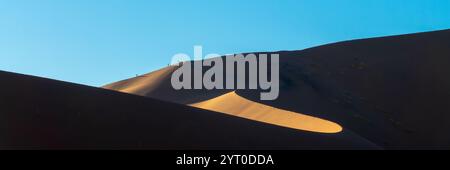 Sagome di persone che scalano la duna di sabbia Big Daddy all'alba a Sossusvlei, parco nazionale Namib Naukluft, paesaggio panoramico della Namibia, Africa Foto Stock
