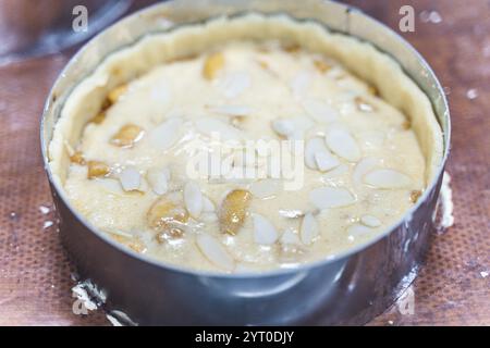 Crostata di mele cruda con petali di mandorla in un piatto da forno sul tavolo di produzione. Foto di alta qualità Foto Stock