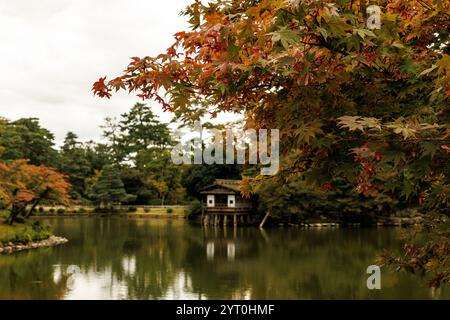 Un paesaggio autunnale splendidamente pittoresco caratterizzato da un fogliame vivace, insieme a una tranquilla cabina sul lago nelle vicinanze Foto Stock