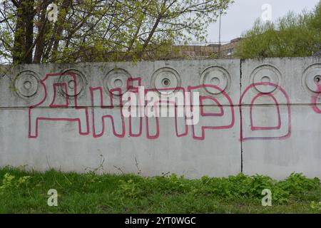 Lettere grigie trasparenti e sottili linee rosse. I graffiti raffiguranti la parola sono dipinti su una recinzione di cemento bianca e grigia. Foto Stock