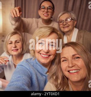 Selfie ritratto di cinque donne anziane allegrhe e sorridenti, amici, che fanno selfie, si incontrano a casa per festeggiamenti accoglienti e bere vino Foto Stock