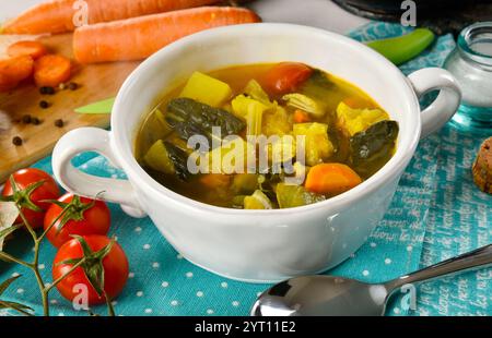 Zuppa di verdure con ortografia in un recipiente di ceramica bianco, con alcuni ingredienti intorno Foto Stock