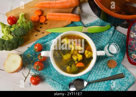 Zuppa di verdure con ortografia in un recipiente di ceramica bianco, con alcuni ingredienti intorno Foto Stock