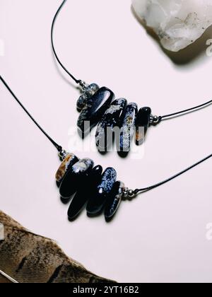 Collana nera con perline irregolari primo piano. Pietra preziosa in agata nera con inserti blu primo piano. Coppia di collane, set di due gioielli in pietra Foto Stock