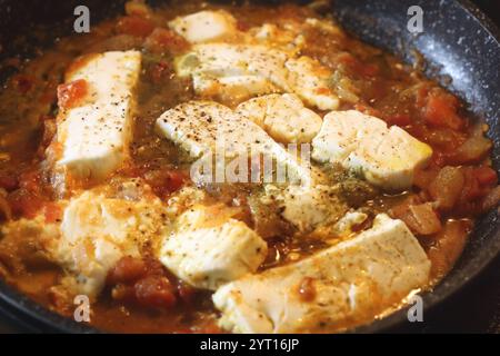Un vibrante shot di Bougiourdi, un piatto tradizionale greco cotto al forno, con cremoso formaggio feta, succosi pomodori, cipolle dolci e piccante colorato Foto Stock