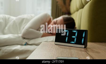 Arrabbiato infastidito stanco ragazza stanca svegliarsi al mattino letto casa camera da letto donna rabbia folle furioso suono forte che suona sveglia sveglia sveglia sveglia Foto Stock