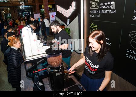 Baku, Azerbaigian, 12 gennaio 2019: Preparazione del caffè per un cliente. Bel giovane in grembiule che prepara il caffè alla macchina da caffè mentre si trova a circa Foto Stock