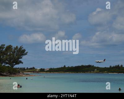 Jet Airliner atterra all'aeroporto internazionale L.F. Wade alle Bermuda. Gli amanti della spiaggia di Clearwater si godranno le calde acque mentre atterrano gli aerei. Foto Stock