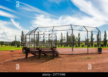 Un campo da baseball con una recinzione intorno. La recinzione è in metallo e ha una piattaforma in legno Foto Stock