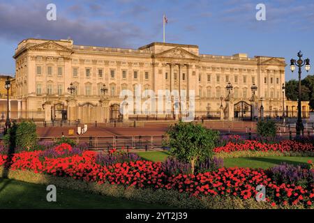 Buckingham Palace si illumina di arancione subito dopo l'alba e di vivaci fiori rossi a Londra, Inghilterra, Regno Unito Foto Stock