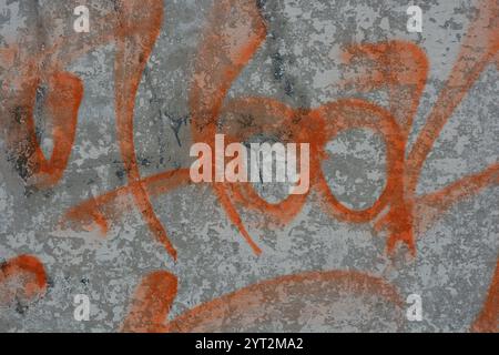 Disegni, graffiti, iscrizioni su una vecchia recinzione in cemento armato, pareti in mattoni. Testo insolito, firma arancione con vernice spray. Foto Stock
