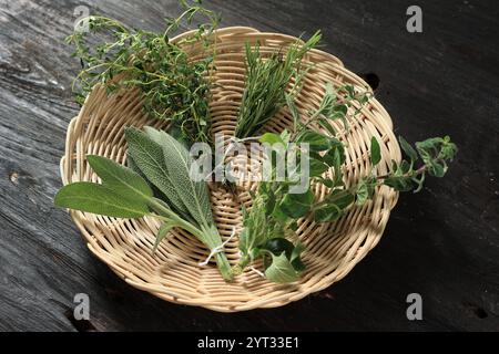 Sage, Rosemary, Oregano e Thyme su Bamboo Plate. Erbe varie su fondo di legno. Foto Stock