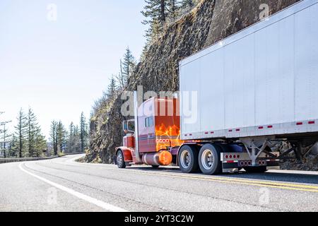 Carro per trasporto lungo semi-camion grande classico arancione con cabina estesa per il riposo del conducente durante il trasporto di carichi in un semi-rimorchio di furgoni asciutti in funzione su Foto Stock