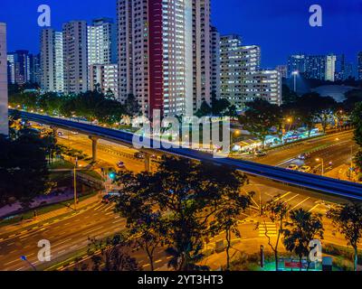 Il paesaggio urbano mostra edifici alti, strade ben illuminate e percorsi sopraelevati che creano un'atmosfera vivace durante la notte. Foto Stock