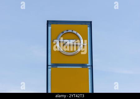 Il logo Opel viene visualizzato su un grande cartello giallo con un cielo azzurro sullo sfondo Foto Stock