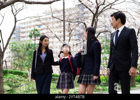 La famiglia passeggia sotto file di ciliegi Foto Stock