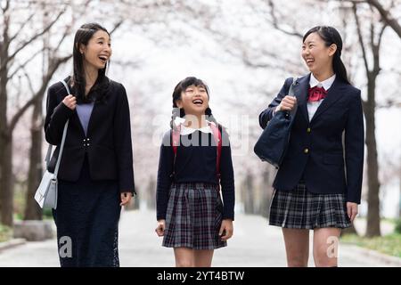 La famiglia passeggia sotto file di ciliegi Foto Stock