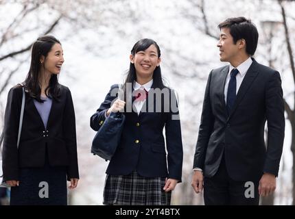 La famiglia passeggia sotto file di ciliegi Foto Stock