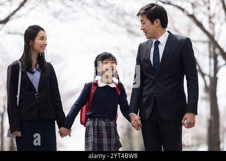 La famiglia passeggia sotto file di ciliegi Foto Stock