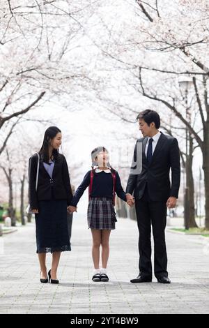 La famiglia passeggia sotto file di ciliegi Foto Stock