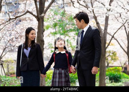 La famiglia passeggia sotto file di ciliegi Foto Stock