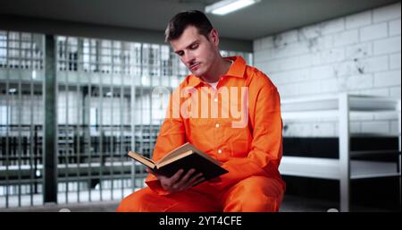 Uomo di preghiera che legge il libro della Bibbia in prigione o in prigione Foto Stock