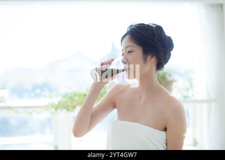 Donna che beve succo di verdura dopo la doccia Foto Stock