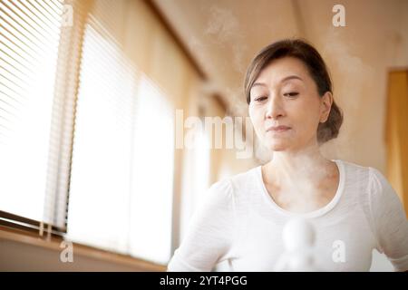 Donna che utilizza un apparecchio per il viso Foto Stock