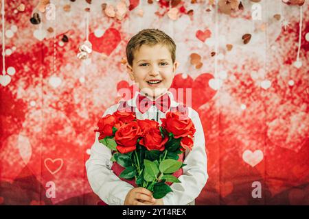 Un ragazzo sorridente in cravatta tiene le rose sullo sfondo del cuore di San Valentino Foto Stock