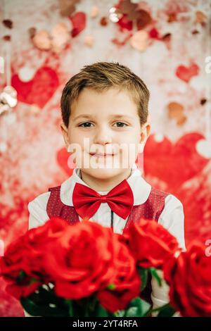 Ragazzo con papillon rosso e gilet con rose, sfondo a tema cuore Foto Stock