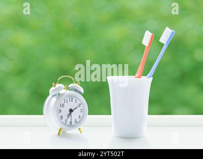 Spazzolino da denti e sveglia sul davanzale Foto Stock