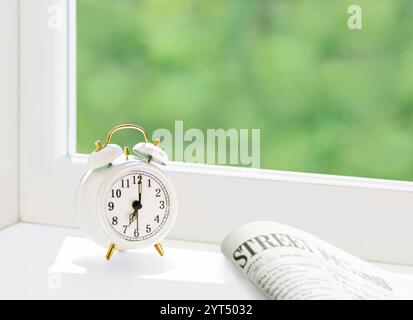 Sveglia e quotidiano sul davanzale Foto Stock