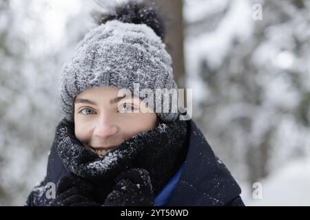 Donna che ricopre il viso con sciarpa di lana nella foresta invernale nelle giornate innevate Foto Stock