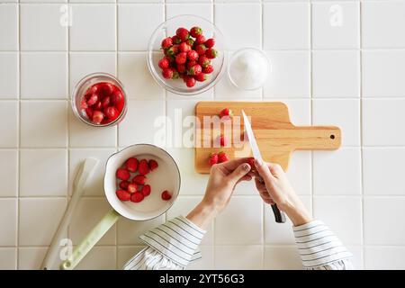 Donna che prepara marmellata di fragole in cucina Foto Stock