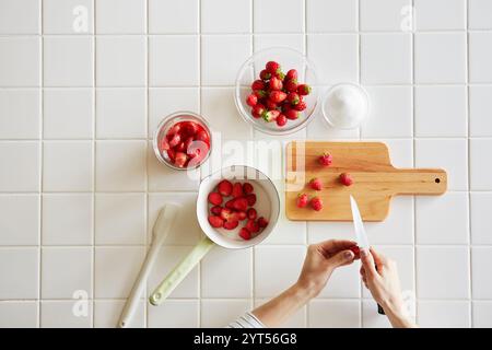 Donna che prepara marmellata di fragole in cucina Foto Stock