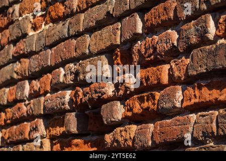 Vista dettagliata delle pareti in mattoni rustici che mostrano texture e colori sotto la luce del sole. Ideale per sfondi o temi architettonici. Foto Stock