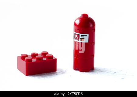 Un mattone rosso Lego è accanto a un idrante rosso. L'idrante del fuoco è rosso e ha un'etichetta bianca. LEGO. Polonia, Varsavia 06.12.2024 Foto Stock