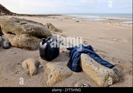 Le Portel (Francia settentrionale), 15 aprile 2024: Lattina di benzina per una piccola barca e maglione appartenente a un migrante abbandonato su una spiaggia tra i Ning Foto Stock