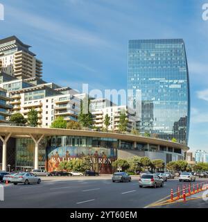 Baku, Azerbaigian - 10 maggio 2024: La Torre di Port Baku, un grattacielo di spicco, è evidenziata contro un cielo azzurro limpido in primavera. Il traffico nelle vicinanze e le aree paesaggistiche migliorano l'ambiente urbano Foto Stock