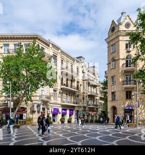 Baku, Azerbaigian - 5 maggio 2024: I visitatori passeggiano piacevolmente lungo via Nizami a Baku, Azerbaigian, circondati da affascinanti negozi e alberi lussureggianti sotto un cielo nuvoloso, creando un'atmosfera urbana vivace Foto Stock