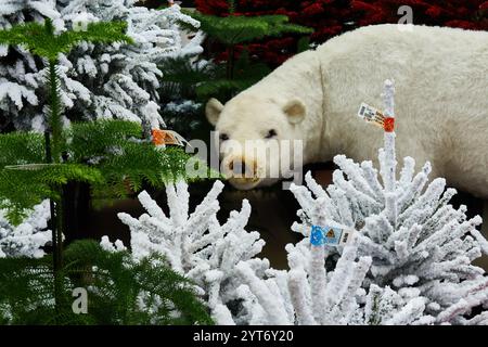 Figurina dell'orso polare in mezzo ai pini artificiali innevati di Natale Foto Stock