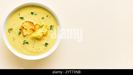 Zuppa di cavolfiore in ciotola su sfondo chiaro con spazio per la copia. Concetto di alimentazione vegetariana o sana. Vista dall'alto, base piatta Foto Stock