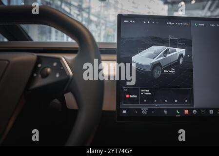 L'immagine mostra un abitacolo Tesla con un ampio touchscreen che visualizza un modello di Cybertruck 3D. L'elegante cruscotto e il volante sono parzialmente visibili Foto Stock