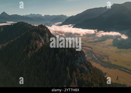 Vista sul Allgäu dalla cima di Falkenstein sopra la cresta di Falkenstein verso est. Un denso mare di nebbia giace sulla pianura con un cielo blu sopra. Si può vedere il confine con l'Austria. Il fiume Vils scorre nella valle. Foto Stock