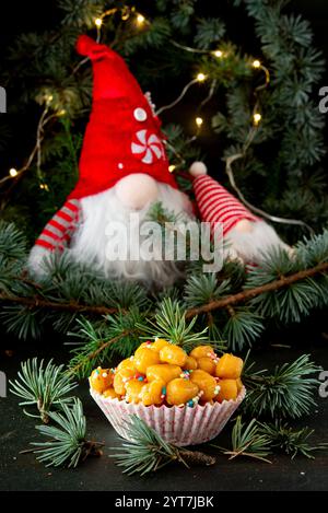 Lo Strufoli, una tradizionale pasticceria italiana con palle di miele, è al centro della scena tra decorazioni natalizie e luci accese, creando uno scenario festivo Foto Stock