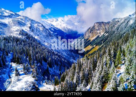 Una vista affascinante della pittoresca valle alpina in una soleggiata giornata invernale. Le nuvole toccano le vette della montagna Foto Stock